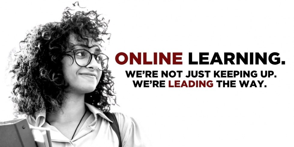 Woman with curly hair and glasses, holding textbooks, witht he words ONLINE LEARNING. WE'RE NOT JUST KEEPING UP. WE'RE LEADING THE WAY.