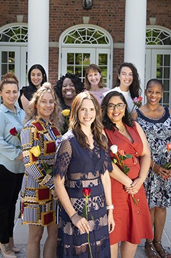 Group of women outside smiling at camera holding roses celebrating an accomplishment