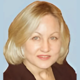 Headshot of Jennifer Vozzella, smiling at the camera. She has shoulder-length blonde hair, is wearing a dark blazer over a light-colored top.